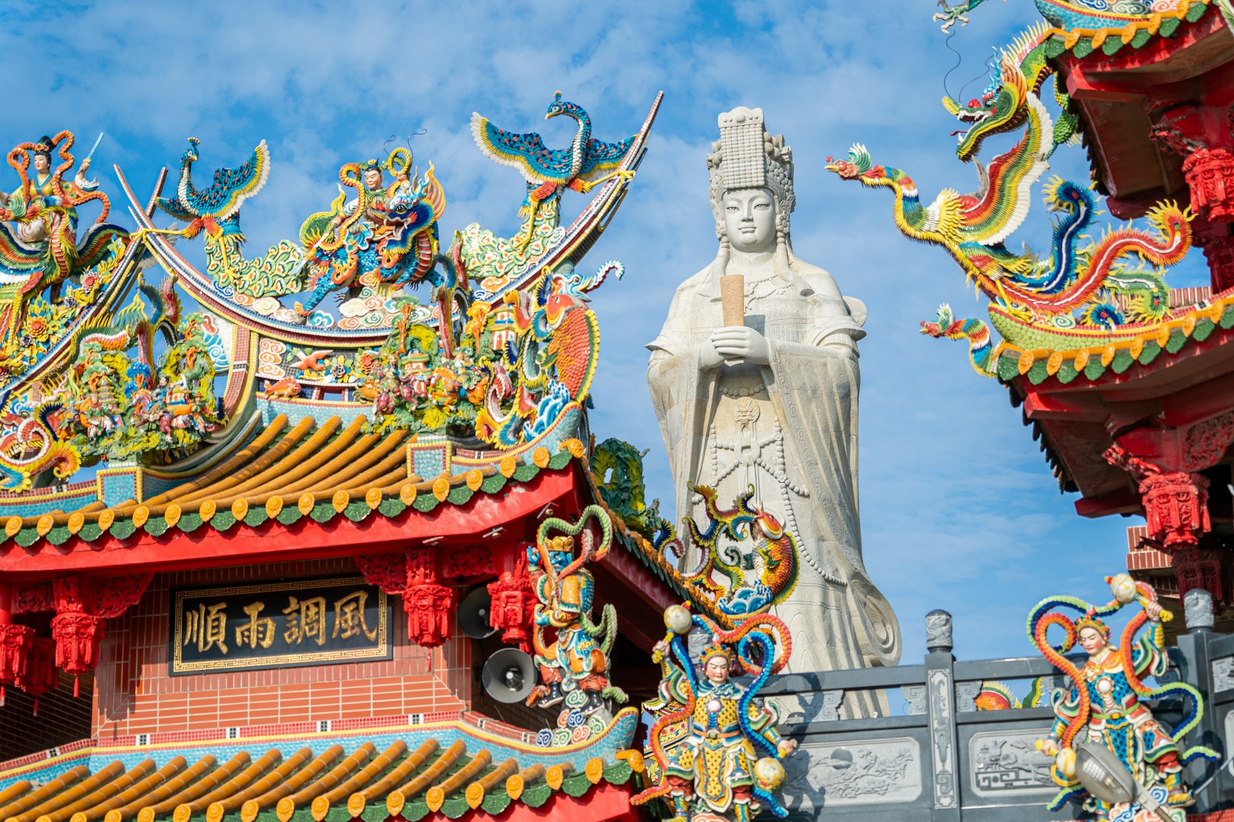 Mazu goddess statue above colourful temple rooftops